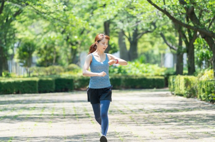 時間をチェックしながら走る女性