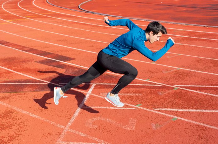 陸上トラックで全力疾走するランナー