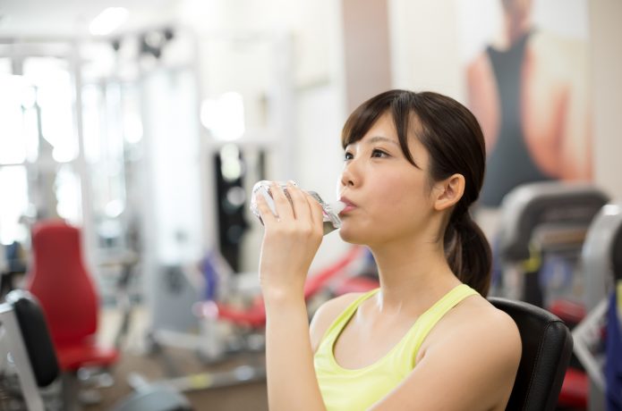 筋トレ前にゼリー飲料を飲む女性