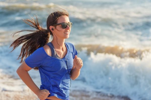 サングラスをかけて海辺を走る女性
