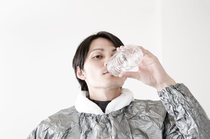 サウナスーツを着て水を飲む男性