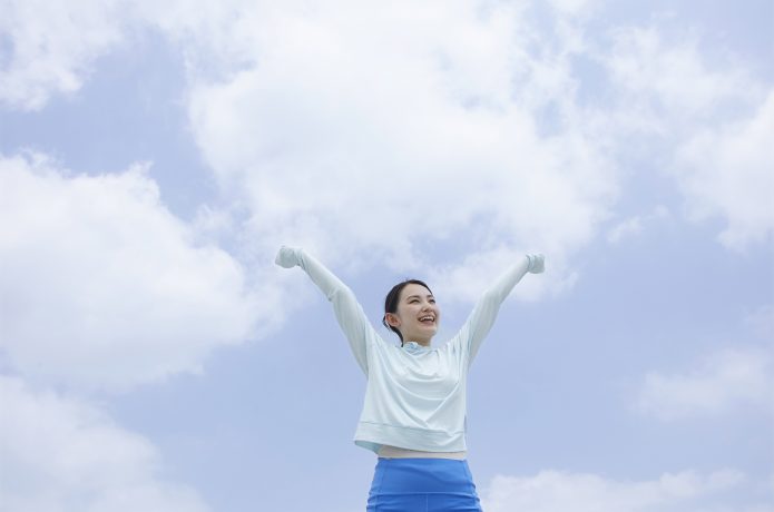 青空の下で笑顔の女性