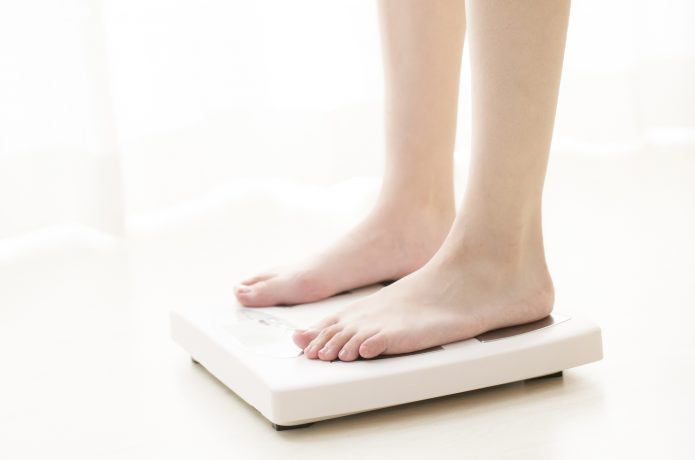 ダイエットを目的に体重計に乗っている女性