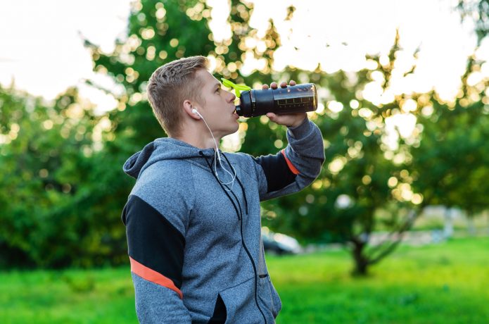 トレーニング中にドリンクを飲む男性