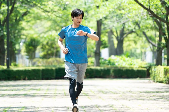 時計で距離を確認しながらランニングする男性