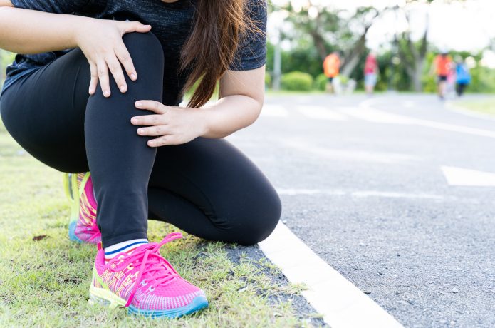 足を痛めているランニング中の女性